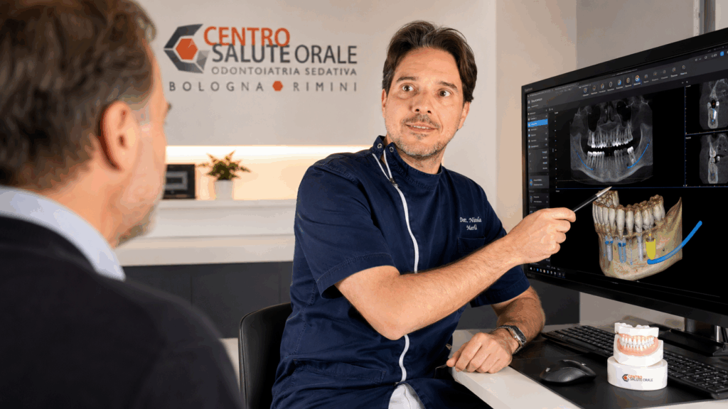 Il dott. Nicola Merli mostra a un paziente una pianificazione implantare digitale 3D con CBCT durante una consulenza per impianti dentali a carico immediato presso il Centro Salute Orale di Bologna e Rimini.